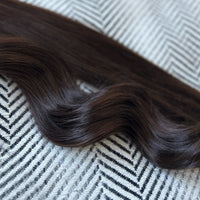 Curly brown human hair extensions on a textured surface