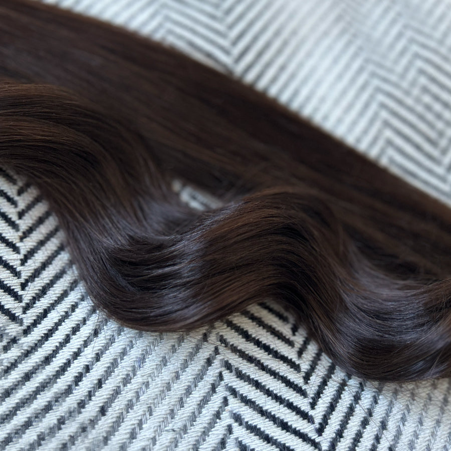 Curly brown human hair extensions on a textured surface
