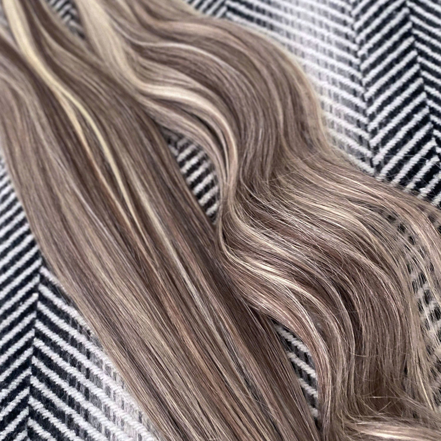 Balayage Mix Shade Human Hair Extensions on a textured background.