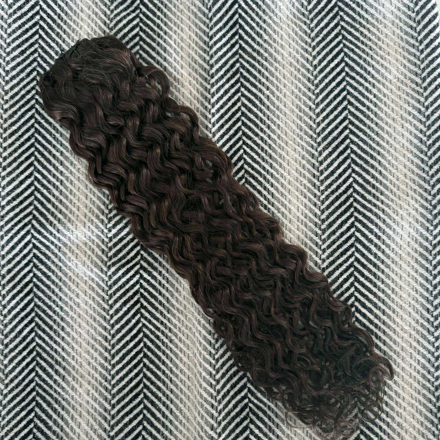 Curly hair extension on a textured gray and white background
