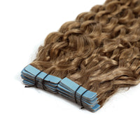 Bundle of curly hair extensions with blue tape on a white background
