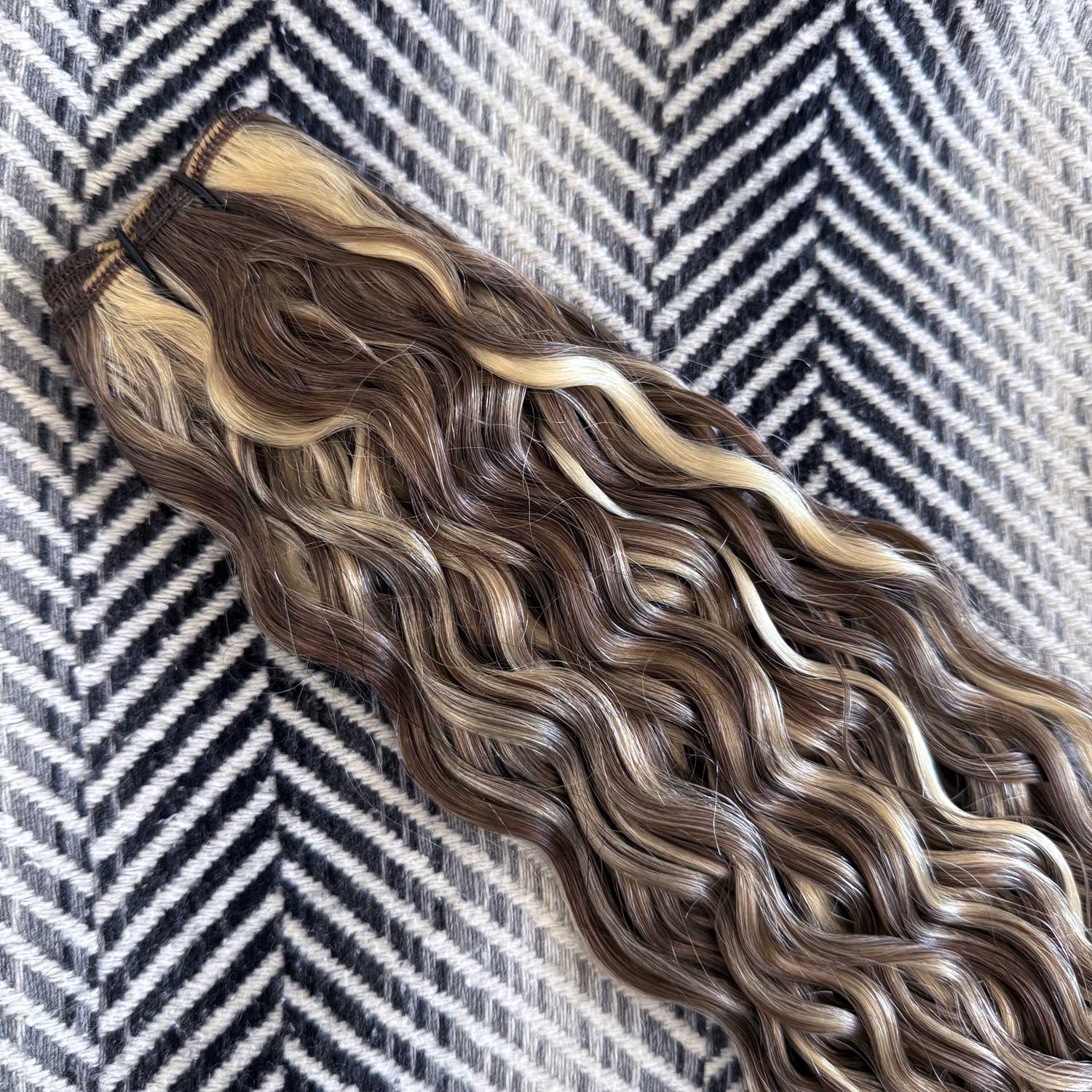 Brown and blonde human hair extensions on a patterned background