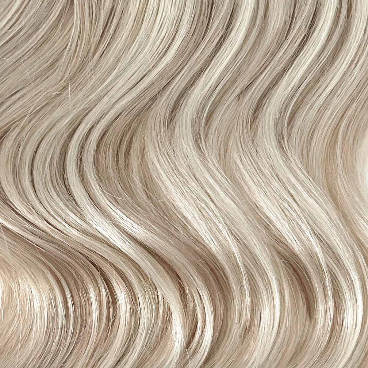 Close-up of wavy hair in a light ash blonde shade, showing the texture and color of the hair strands.