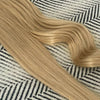 Sandy Blonde hair extensions on a patterned fabric background