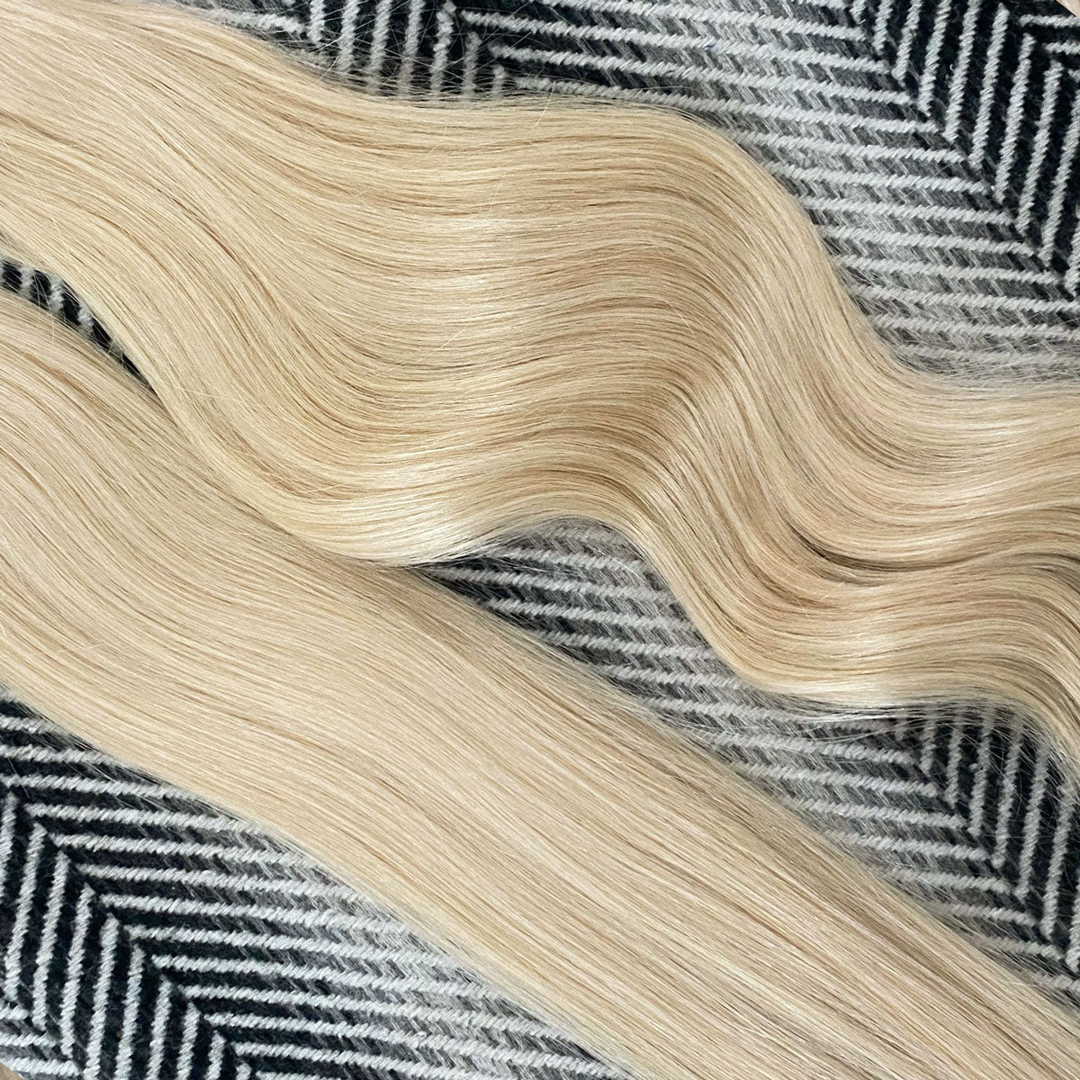 Blonde hair extensions on a textured black and white patterned fabric background