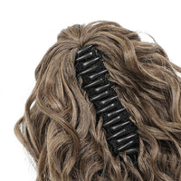 Black hair clip in wavy brown hair on a white background