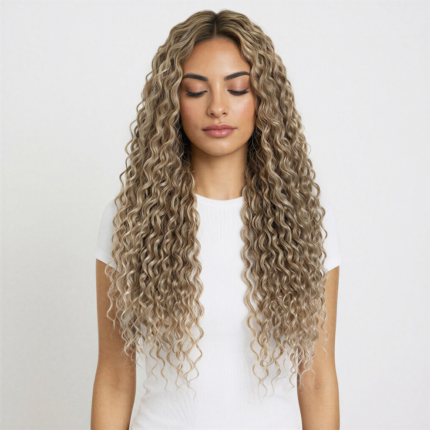 Woman with long, wavy beige blonde curly hair extensions against a white background