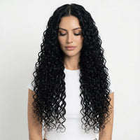 Woman with long, black, curly hair extensions wearing a white top on a light gray background