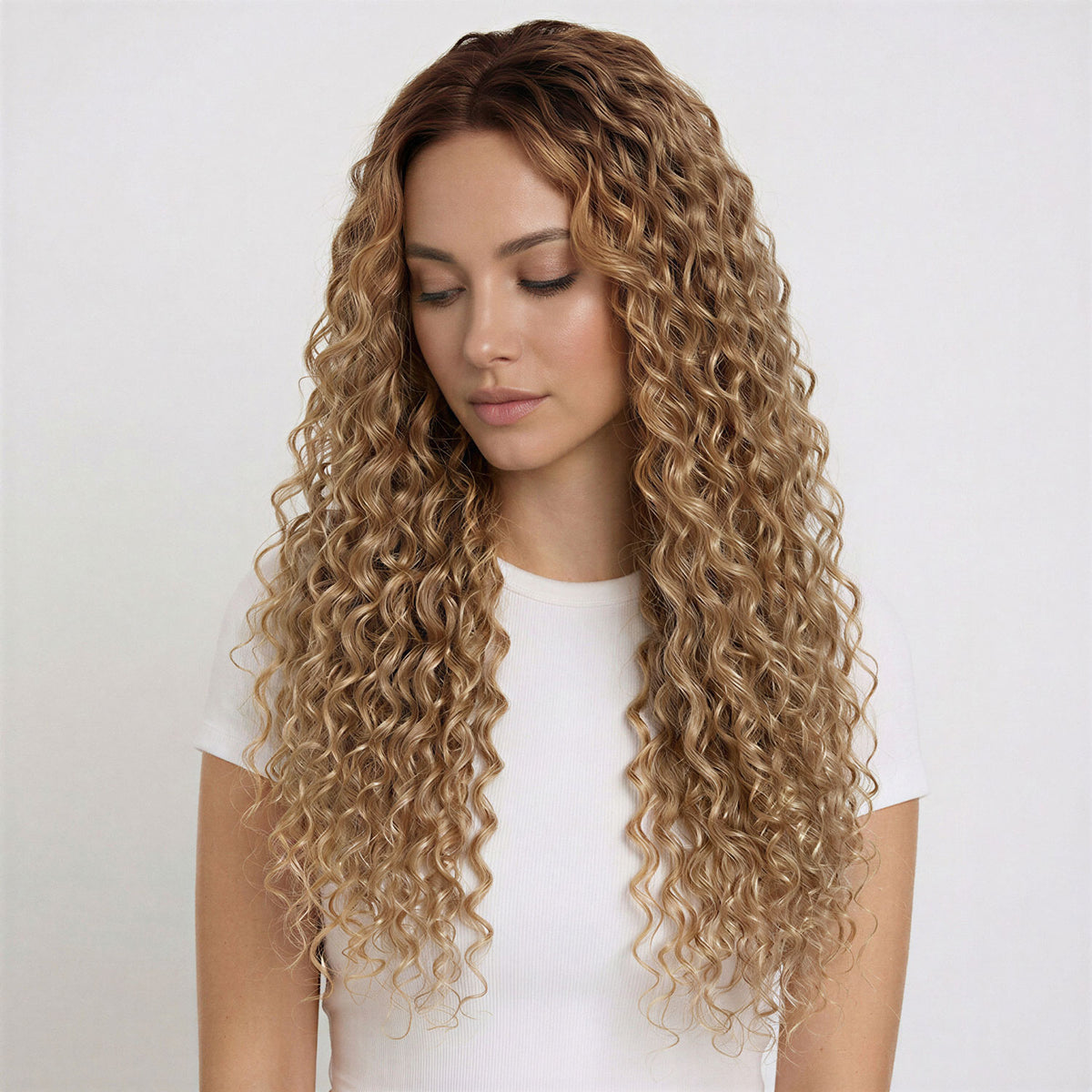 Woman with long, wavy naturl blonde curly hair extensions wearing a white top on a light background