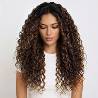Woman with long, curly hair extensions wearing a white top on a light background