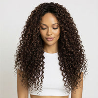 Woman with long, curly hair extensions wearing a white top on a light background
