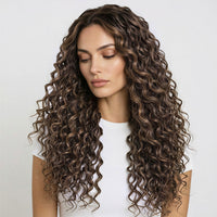 Woman with long, wavy ash and dark brown curly hair extensions wearing a white top on a light gray background