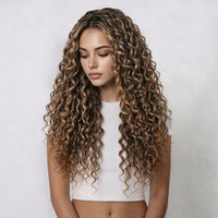 Woman with long, curly hair extensions wearing a white top against a plain background