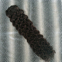 Curly hair extension on a textured gray and white background