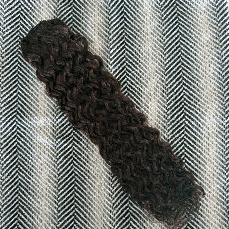 Curly hair extension on a textured gray and white background