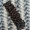 Brown curly hair extensions on a herringbone patterned surface