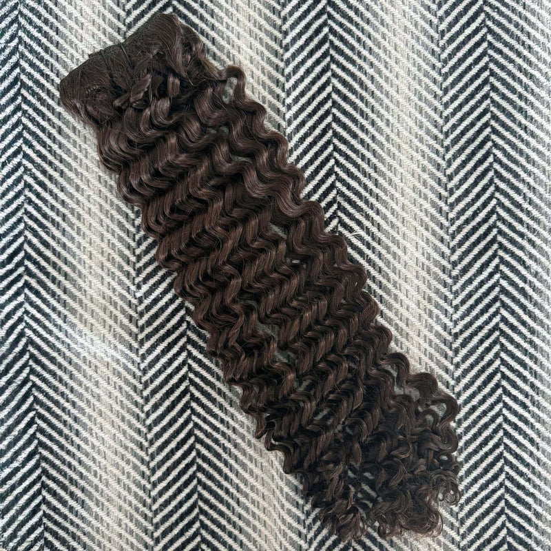 Brown curly hair extensions on a herringbone patterned surface