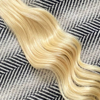 Blonde hair extensions on a textured black and white background