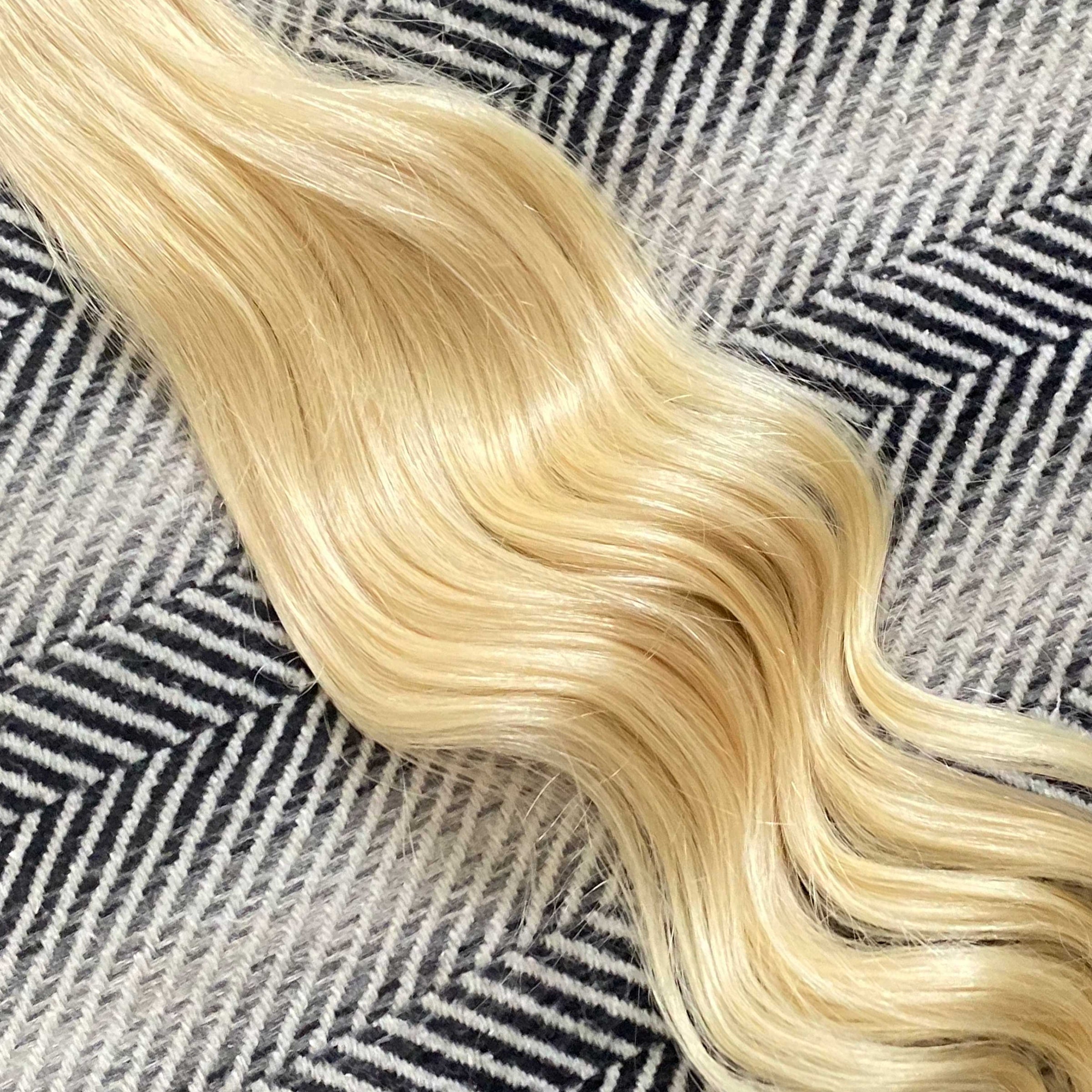 Blonde hair extensions on a textured black and white background