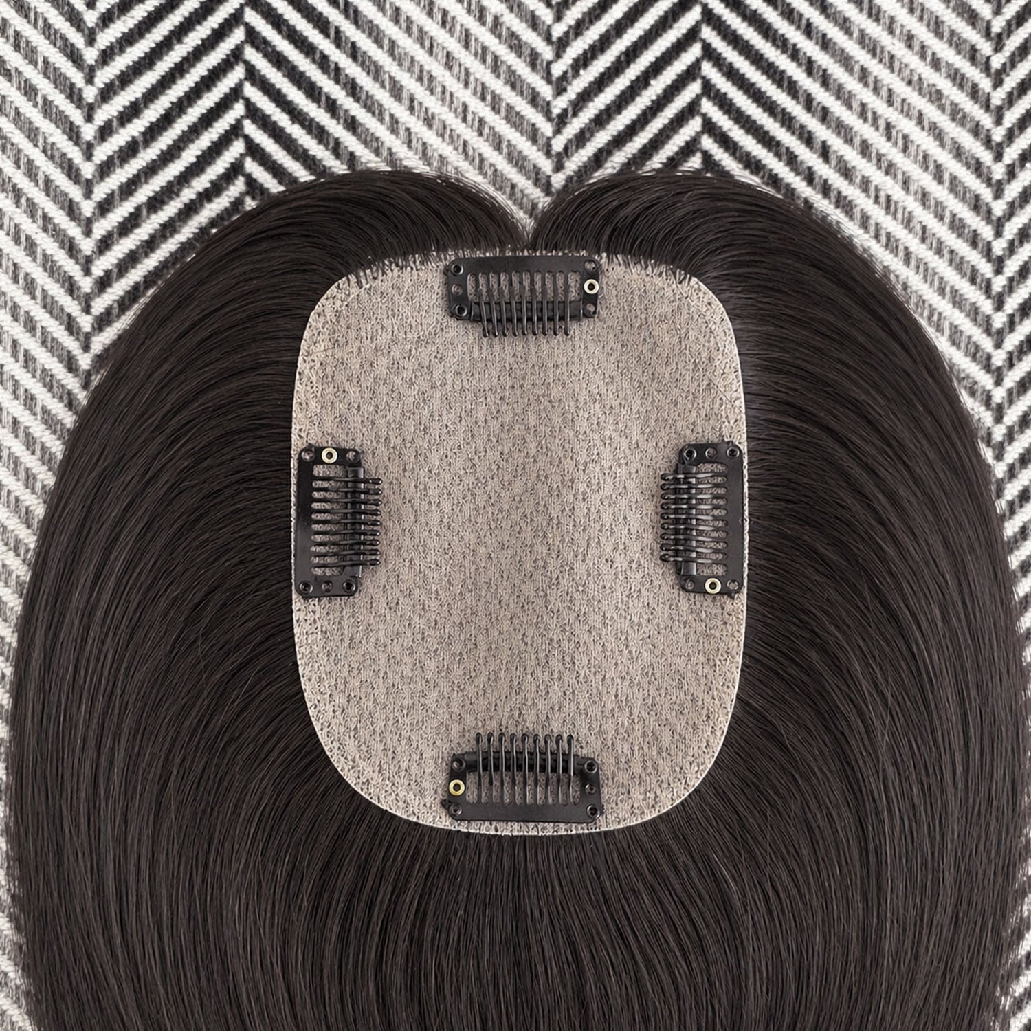 Hair extension with a gray base and black hair on a patterned background