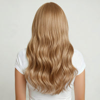 Person with long, natural blonde hair extensions wearing a white shirt on a light background