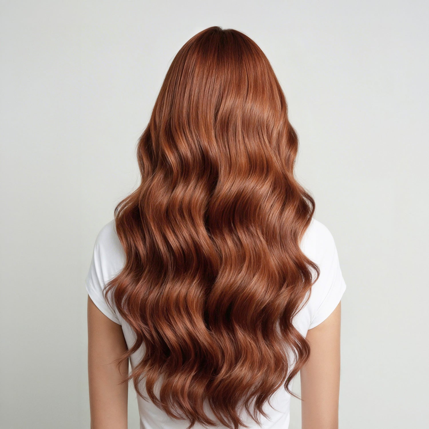 Person with long, wavy, copper brown hair on a plain background