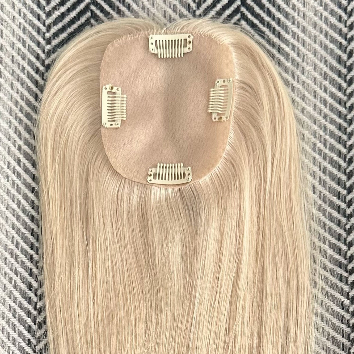 Blonde hair extension with clips on a textured background