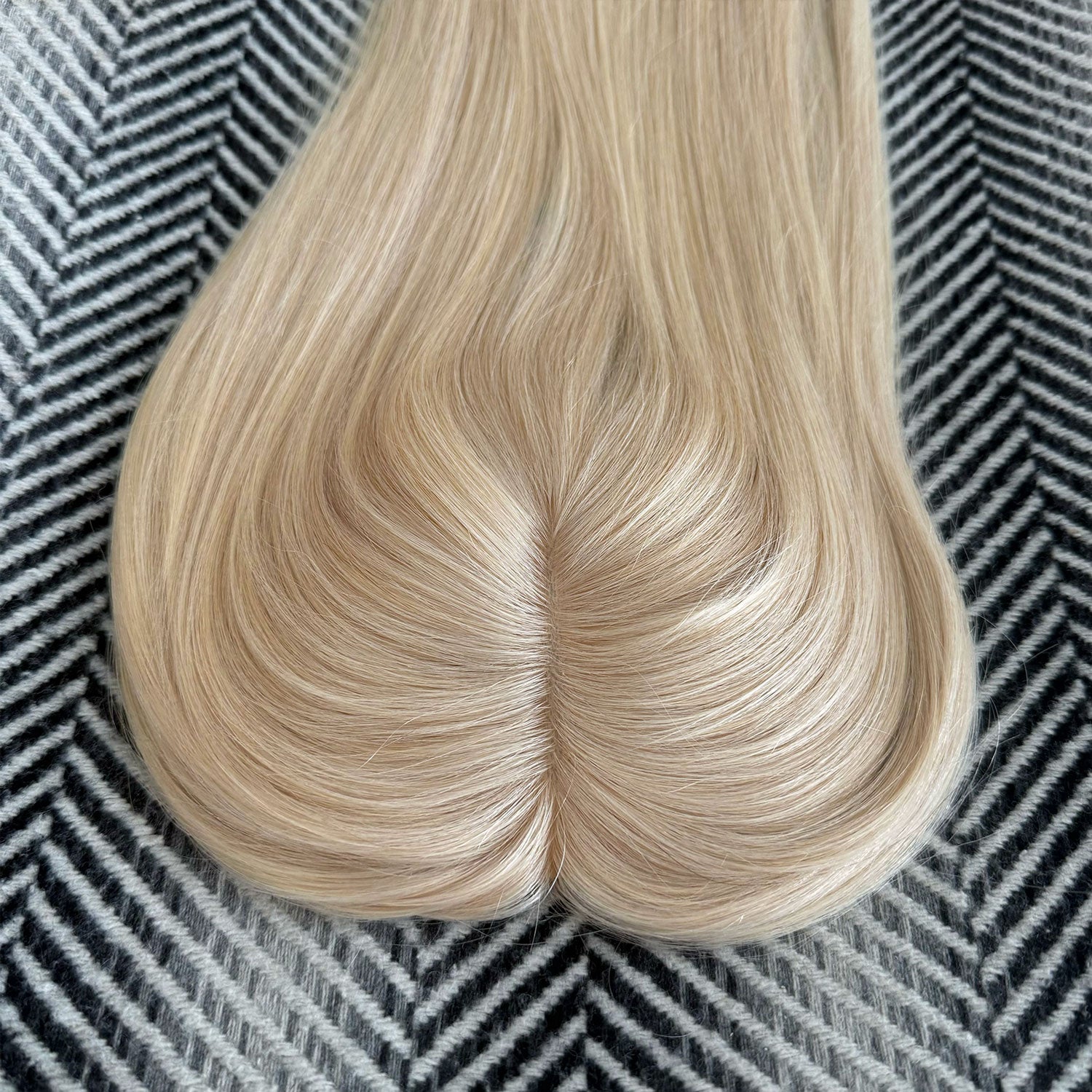 Blonde hair extension on a textured black and white background