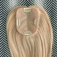 Blonde hair extension with clips on a patterned background