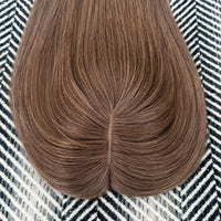 Cinnamon Brown hairpiece on a patterned fabric background