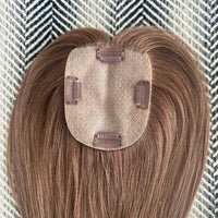 Brown hair extension with clips on a textured background