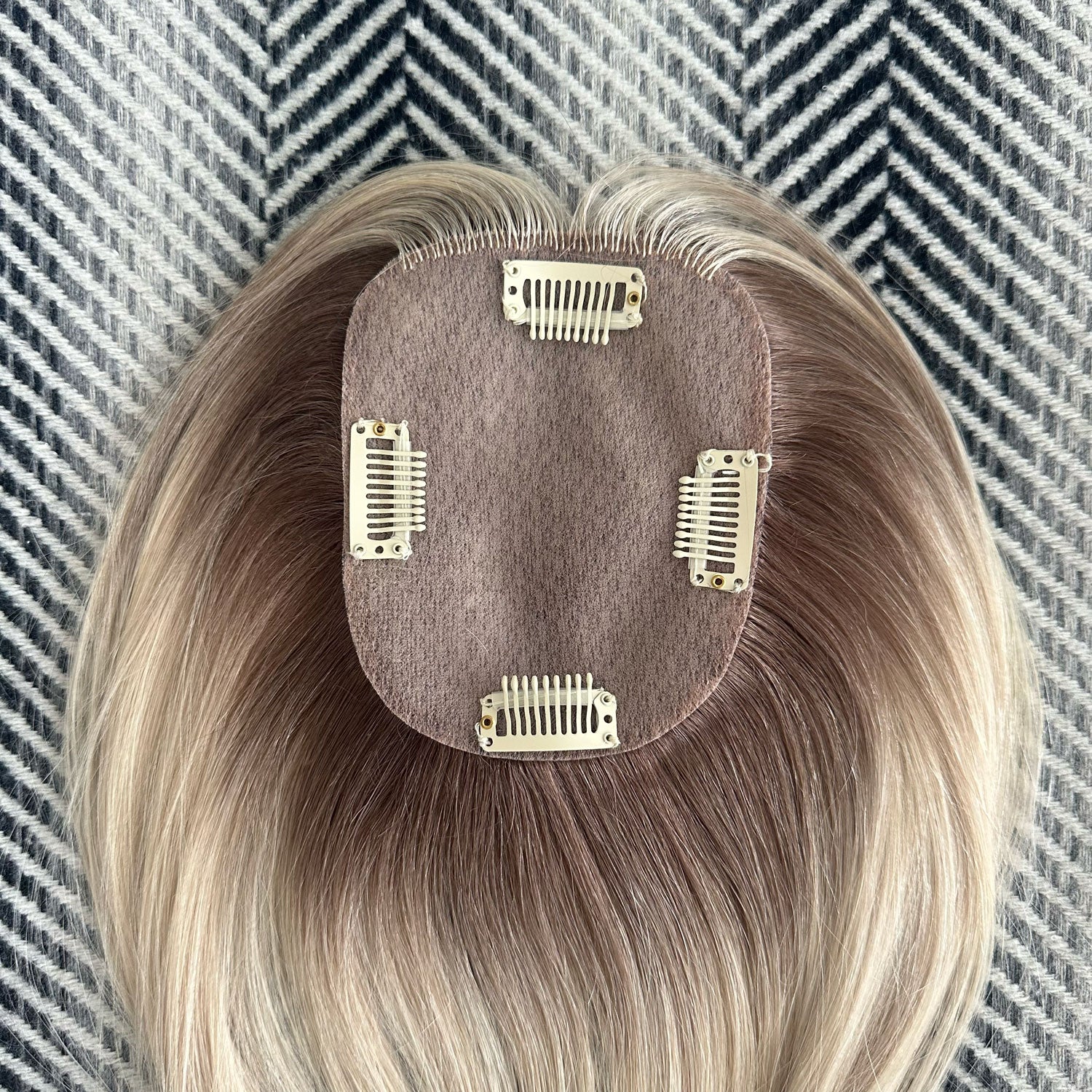 Blonde hair extension with clips on a textured background