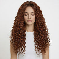 Woman with long, wavy copper hair extensions wearing a white top on a light gray background
