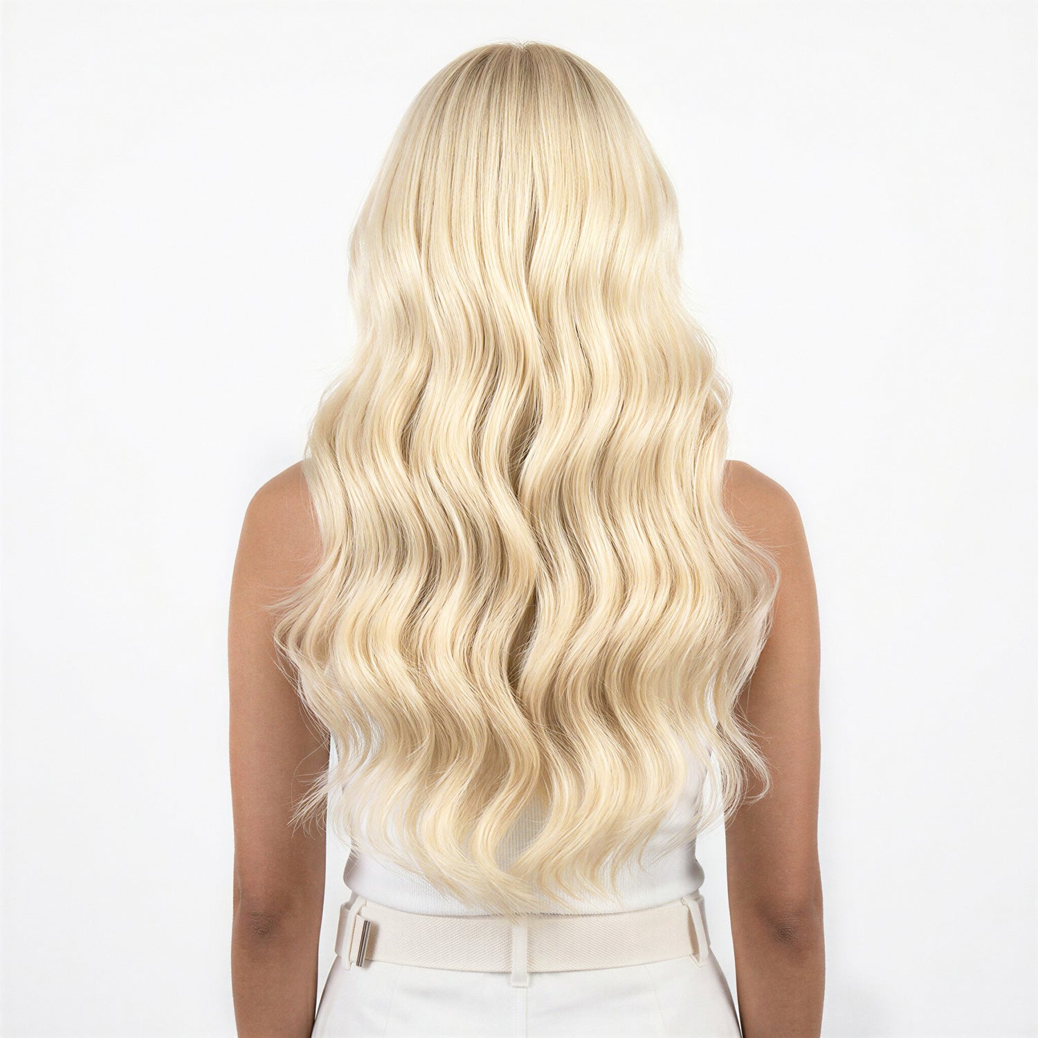 Person with long, wavy vanilla blonde hair extensions on a white background