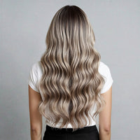 Person with long, wavy hair extensions in a neutral setting